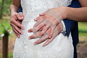 Loving couple wedding fingers golden rings on bride groom hands on white dress