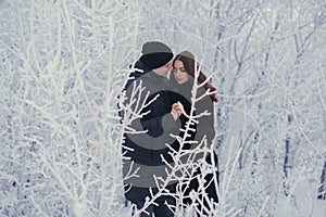 A loving couple on a winter walk. Snow love story, winter magic. Man and woman on the frosty street. The guy and the girl are rest