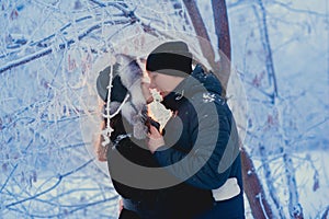 A loving couple on a winter walk. Snow love story, winter magic. Man and woman on the frosty street. The guy and the girl are rest