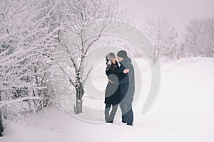 A loving couple on a winter walk. Snow love story, winter magic. Man and woman on the frosty street. The guy and the girl are rest