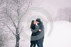 A loving couple on a winter walk. Snow love story, winter magic. Man and woman on the frosty street. The guy and the girl are rest