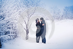 A loving couple on a winter walk. Snow love story, winter magic. Man and woman on the frosty street. The guy and the girl are rest