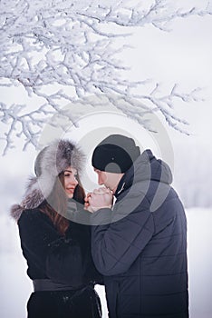 A loving couple on a winter walk. Snow love story, winter magic. Man and woman on the frosty street. The guy and the girl are rest