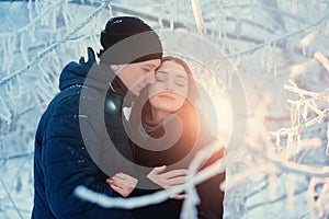 A loving couple on a winter walk. Snow love story, winter magic. Man and woman on the frosty street. The guy and the girl are rest
