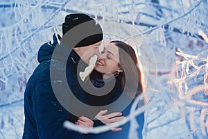 A loving couple on a winter walk. Snow love story, winter magic. Man and woman on the frosty street. The guy and the girl are rest