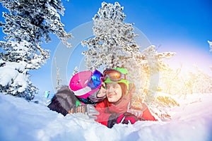 Loving couple woman and man having fun and fooling around in winter forest. Skier and snowboarder on background of blue