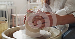 Loving couple working on poterry wheel in pottery workshop