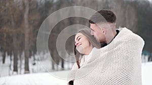 Loving couple wrapped in plaid sitting outside in winter