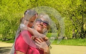 Loving cute granddaughter hugging her grandmother. Happy family.  Having good times with grandparent outdoors