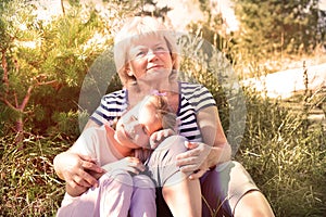 Loving cute granddaughter hugging her grandmother. Happy family.  Having good times with grandparent outdoors