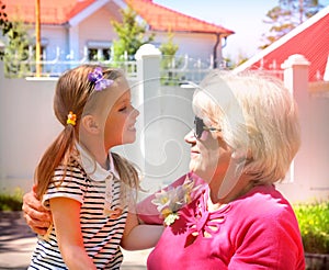 Loving cute granddaughter hugging her grandmother. Happy family.  Having good times with grandparent outdoors