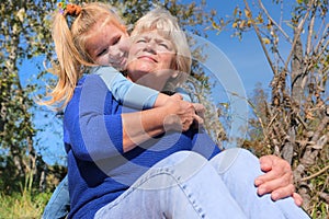 Loving cute granddaughter hugging her grandmother. Happy family.  Having good times with grandparent outdoors