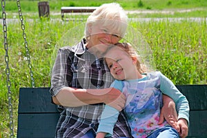 Loving cute granddaughter hugging her grandmother. Happy family.  Having good times with grandparent outdoors. Soft focus