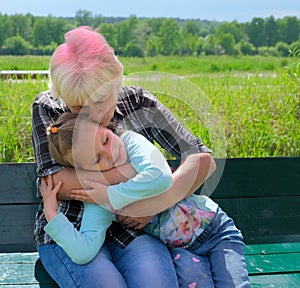 Loving cute granddaughter hugging her grandmother. Happy family.  Having good times with grandparent outdoors. Soft focus