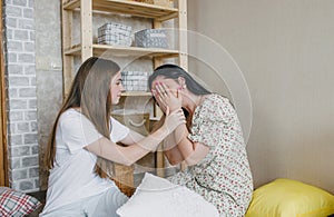 a loving daughter comforts her sad mom sitting in a room on the floor