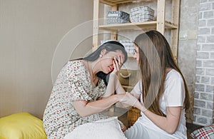 a loving daughter comforts her sad mom sitting in a room on the floor