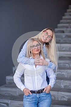 Loving daughter hugs Senior mom and stand on the stairs. Happy mother`s day. The family spends time together. Love and