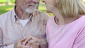 Loving elderly couple looking each other, man and woman holding hands, affection