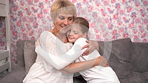 A loving elderly grandmother hugs and kisses her teenage granddaughter.
