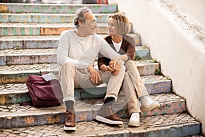 Loving Elderly Tourists Couple Pausing Resting On Colorful Steps Outdoor