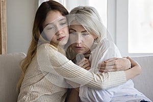 Loving empathetic pre-teen daughter cuddling her mature frustrated mother