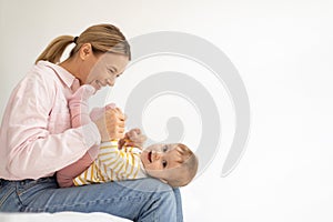 Loving european mother playing with baby daughter, taking care of child, enjoying tender moment, side view, free space