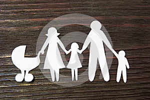 Loving family holding hands. Paper figures on a background of mahogany.