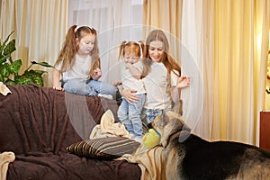 Loving family with mother, daughter sisters and big dog in living room. Woman mom, small child girl, female teenager who