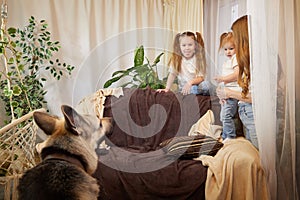 Loving family with mother, daughter sisters and big dog in living room. Woman mom, small child girl, female teenager who