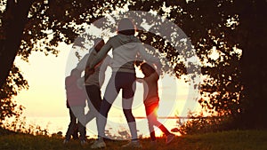 Loving family walks in the countryside during sunset. Mom and Dad hug and play with their son and daughter. The concept