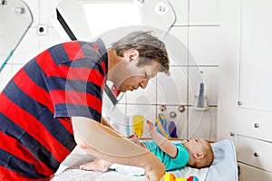 Loving father changing diaper of his newborn baby daughter.