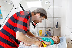 Loving father changing diaper of his newborn baby daughter.