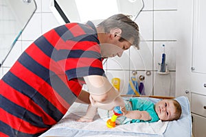 Loving father changing diaper of his newborn baby daughter.