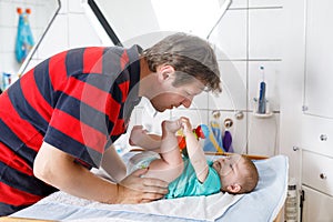 Loving father changing diaper of his newborn baby daughter.