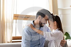 Loving father and little daughter touching foreheads, enjoying tender moment