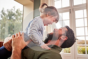 Loving Father Playing With Laughing Down Syndrome Daughter At Home Together