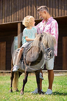 Loving father touching head of son sitting on horse