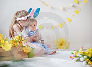 Loving girl and her little brother wearing bunny ears in Easter decor