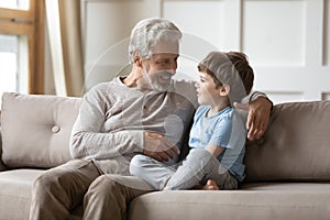 Loving granddad sit on sofa talking with small grandson photo