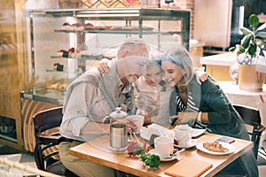 Loving granddaughter wearing white shirt hugging her grandparents