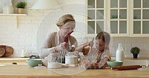 Loving grandmother teach little cute granddaughter to cook