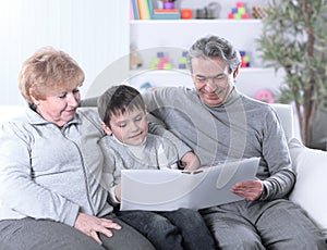 Loving grandparents with grandchild sitting on sofa