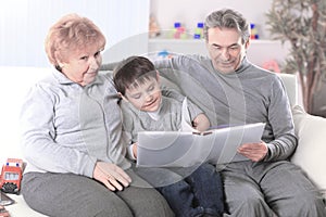 Loving grandparents with grandchild sitting on sofa