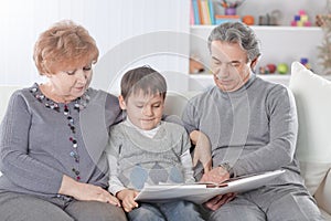 Loving grandparents with grandchild sitting on sofa