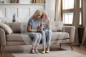 Loving grownup daughter comfort upset mom at home