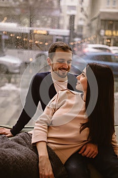 Loving happy couple. Guy and his girlfriend dressed in in sweaters and jeans sitting close to each other on the