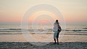 Loving Happy Couple is and Laughing Whirling on Sea Beach at Sunset in Summer