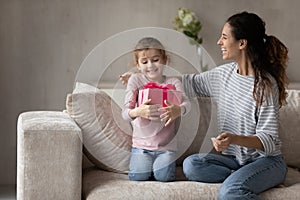 Loving happy mother congratulating little daughter, presenting gift box
