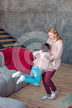 Loving happy mother lifting her daughter while dancing at home