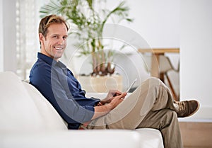 Loving his laid-back day at home. a handsome man using his tablet while sitting on the sofa at home.